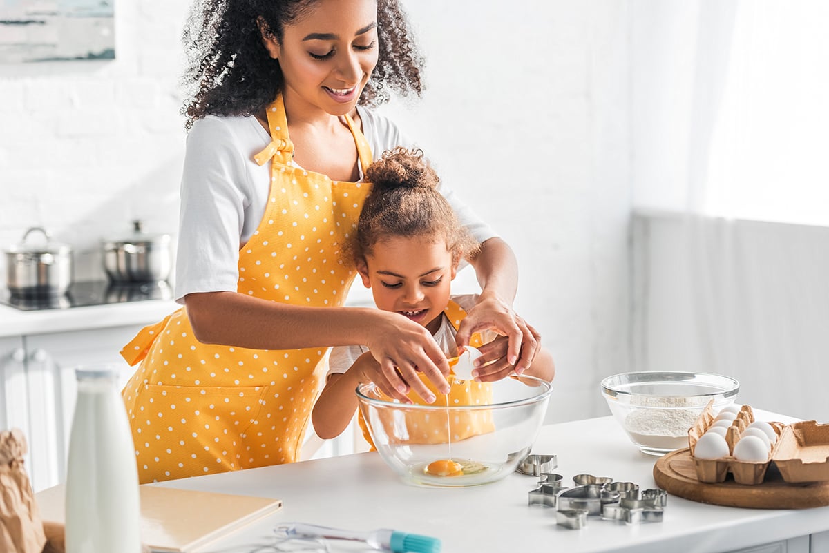 Mother and daughter cracking an egg in a bowl