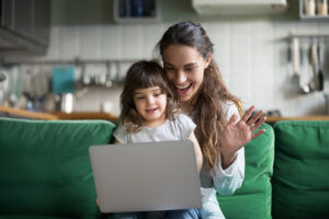 Mother and child smiling and sitting on green sofa looking at computer for OIT office hours at Latitude